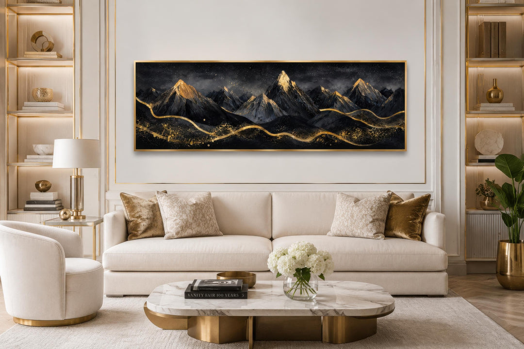 Black and gold mountain landscape canvas art hanging above a cream sofa in a modern living room.