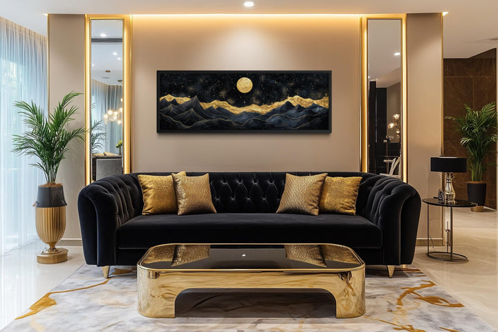 A panoramic canvas print of a moonlit mountain landscape in black and gold hangs in a luxury room.