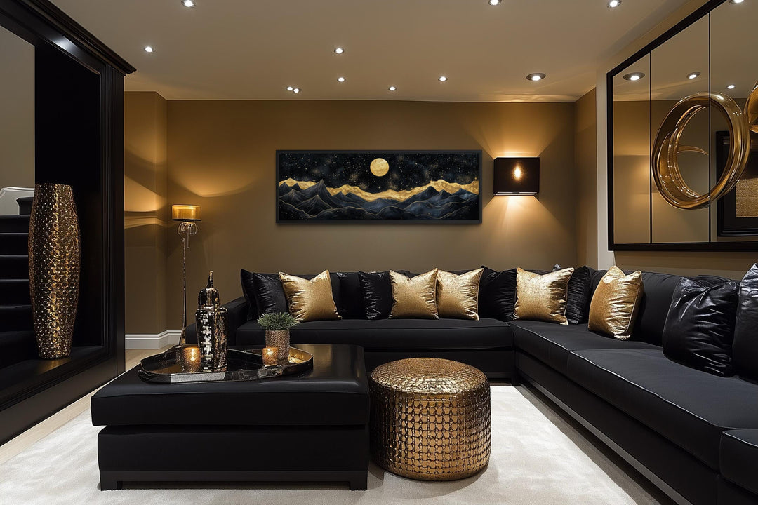 Black and gold mountain landscape canvas print with a full moon above a modern black sofa.