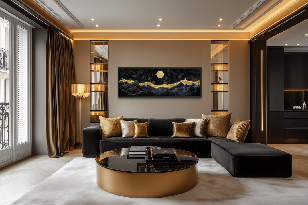 A panoramic canvas print of a moonlit mountain landscape in black and gold hangs in a luxury room.