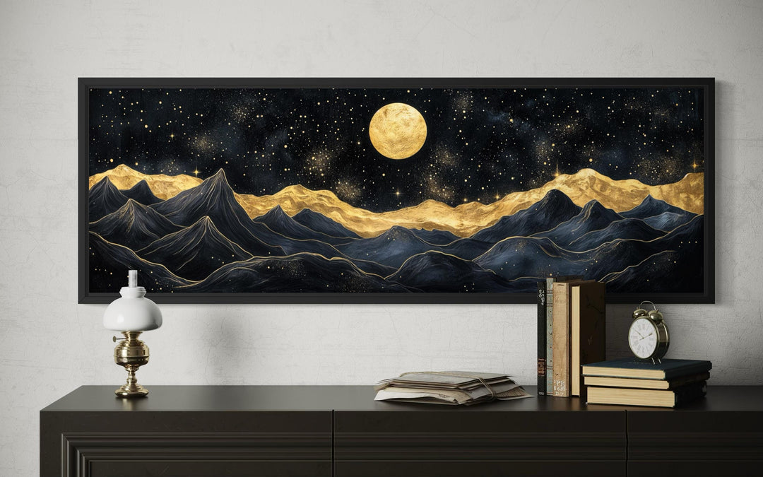 A framed horizontal canvas print of abstract black and gold mountains under a full golden moon.