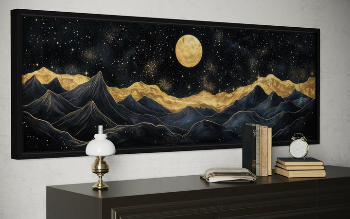 A wide horizontal canvas print of abstract black and gold mountains under a full golden moon.
