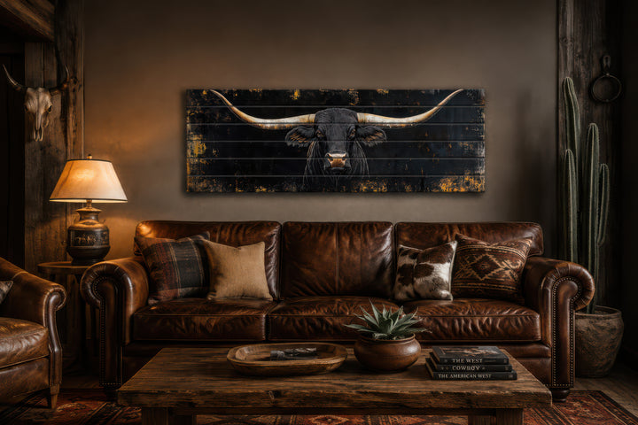 Black Texas Longhorn printed on horizontal rustic wood planks above a leather sofa.