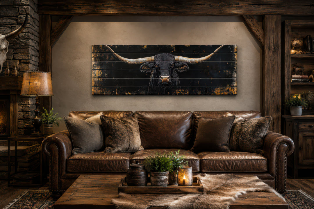 Black Texas Longhorn printed on horizontal rustic wood planks above a leather sofa in a cabin.