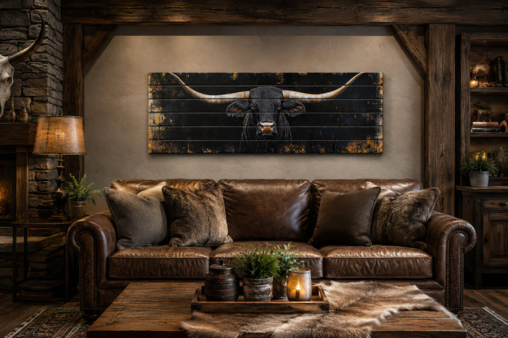 Black Texas Longhorn printed on horizontal rustic wood planks above a leather sofa in a cabin.