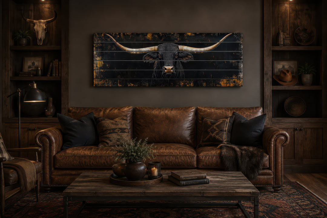 Black Texas Longhorn printed on horizontal wooden planks above a brown leather sofa.