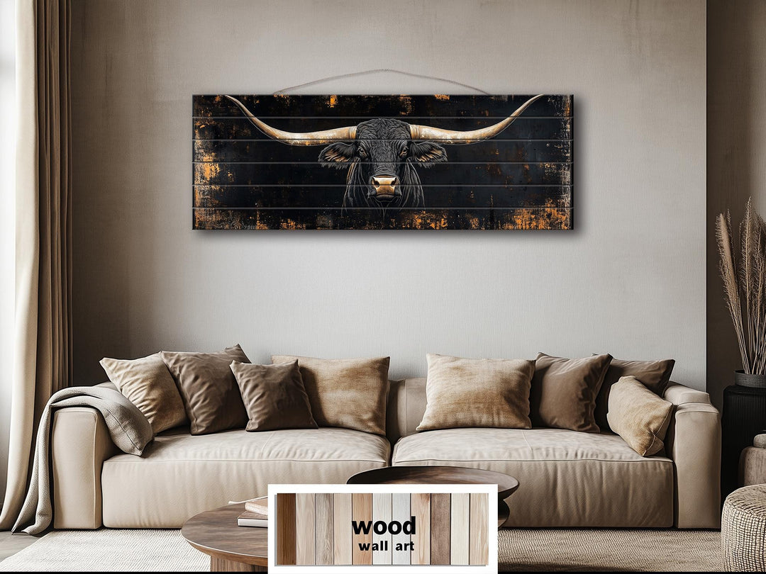 Black Texas Longhorn printed on a long horizontal wood plank wall art above a tan sofa.