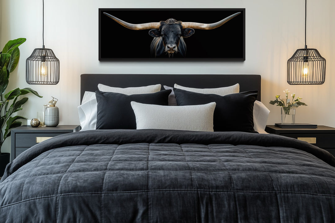 Panoramic framed canvas wall art of a black Texas longhorn steer hanging above a bed.