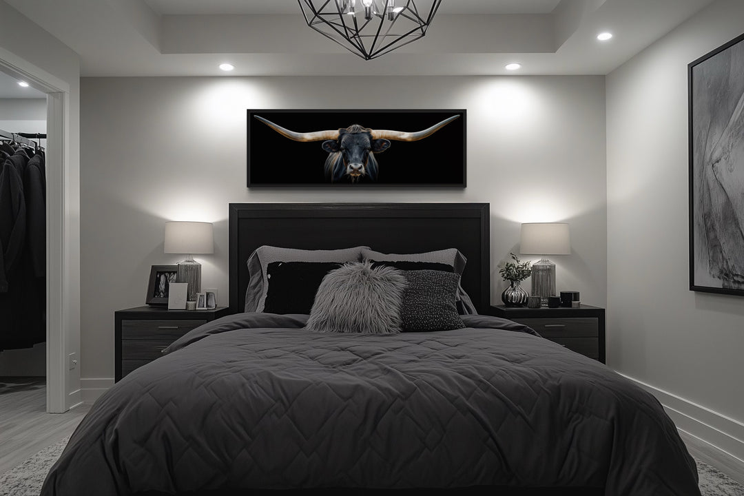 Panoramic framed canvas wall art of a black Texas longhorn steer hanging above a bed.