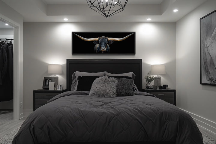 Panoramic framed canvas wall art of a black Texas longhorn steer hanging above a bed.