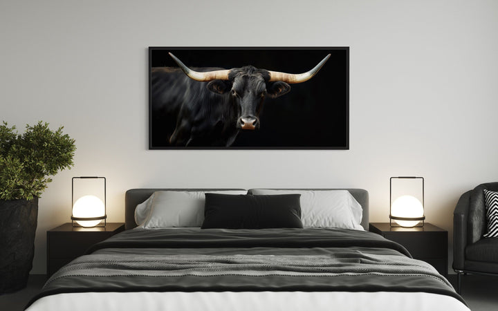 Extra large framed canvas print of a black Texas Longhorn bull hanging above a modern bed.