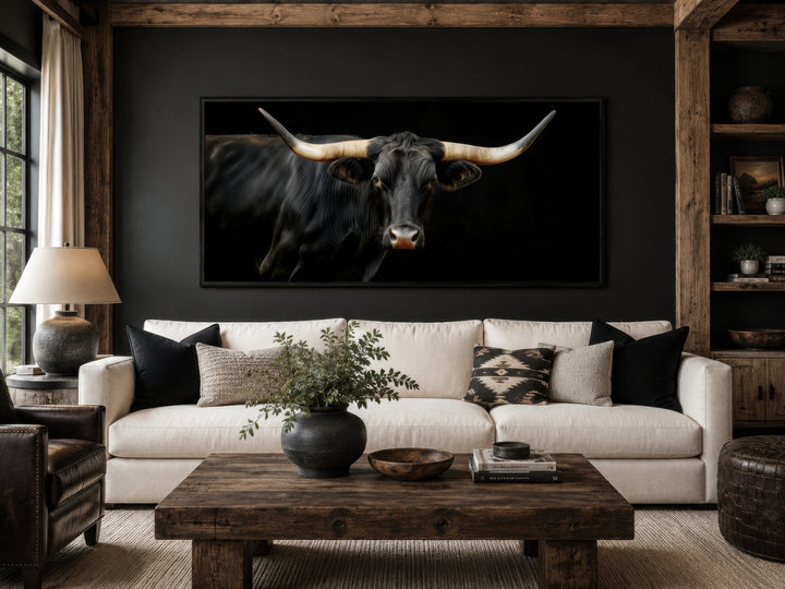 Extra large framed canvas print of a black Texas Longhorn bull in a rustic living room.