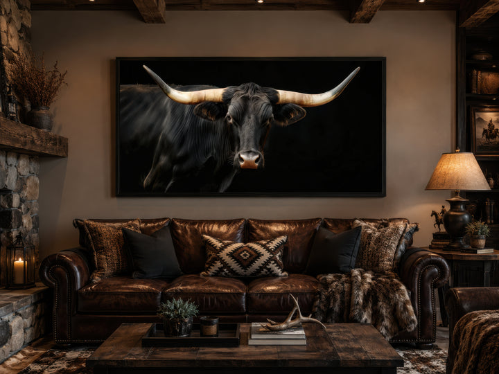 Extra large framed canvas print of a black Texas Longhorn bull above a brown leather sofa.