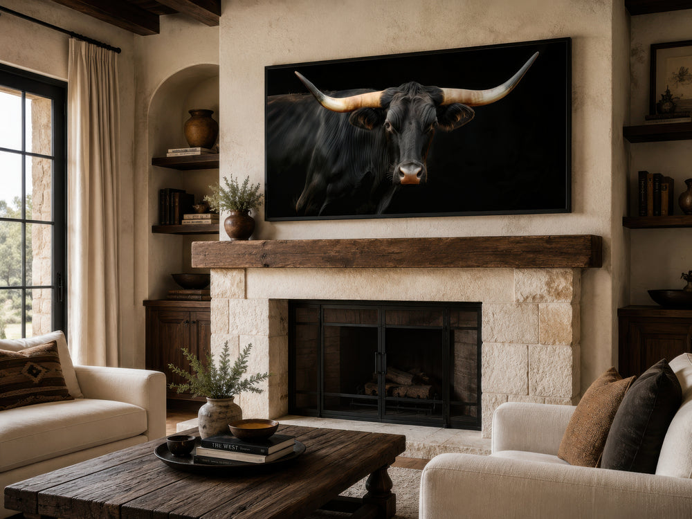 Extra large framed canvas print of a black Texas Longhorn bull above a rustic stone fireplace.
