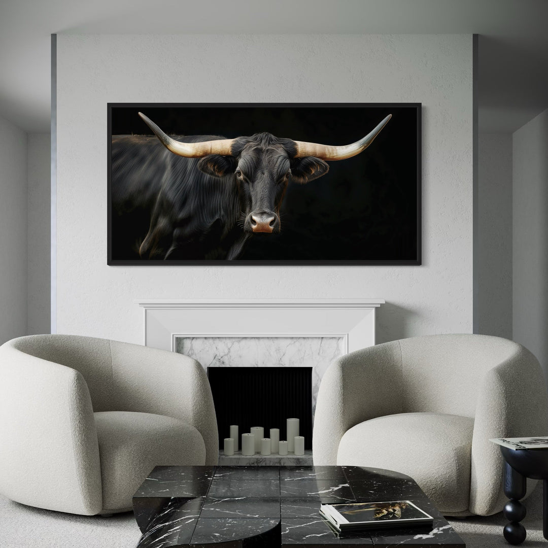 Extra large framed canvas print of a black Texas Longhorn bull above a white marble fireplace.