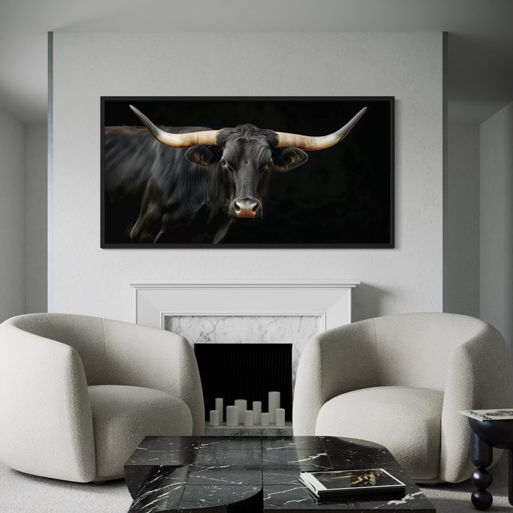Extra large framed canvas print of a black Texas Longhorn bull above a white marble fireplace.