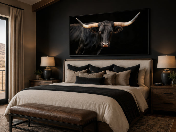 Extra large framed canvas print of a black Texas Longhorn bull above a bed in a rustic bedroom.
