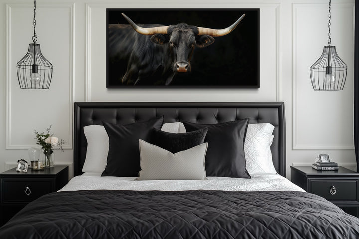Extra large framed canvas print of a black Texas Longhorn bull above a bed in a modern bedroom.