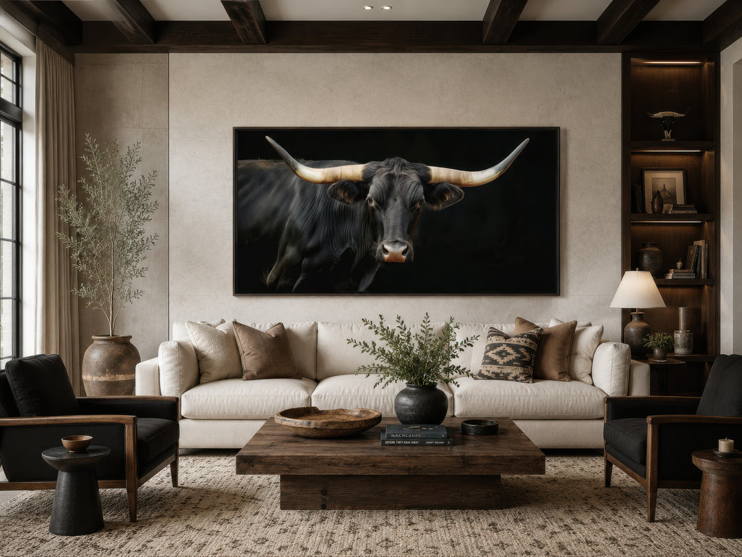 Extra large framed canvas print of a black Texas Longhorn bull above a sofa in a rustic living room.