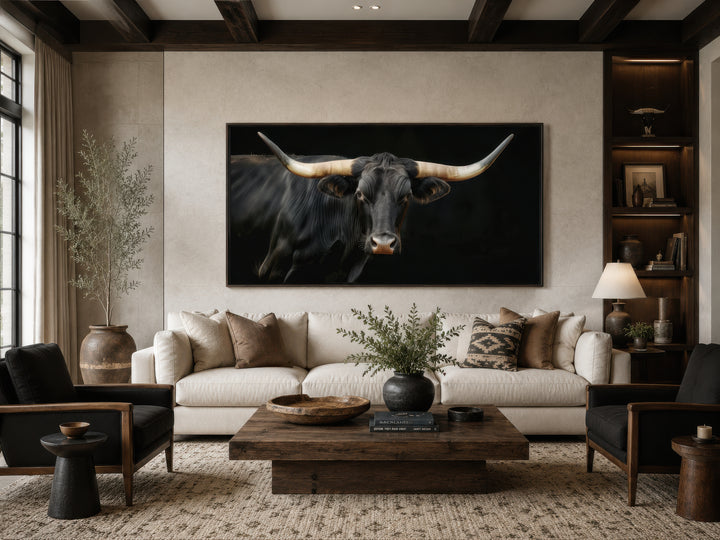 Extra large framed canvas print of a black Texas Longhorn bull above a sofa in a rustic living room.