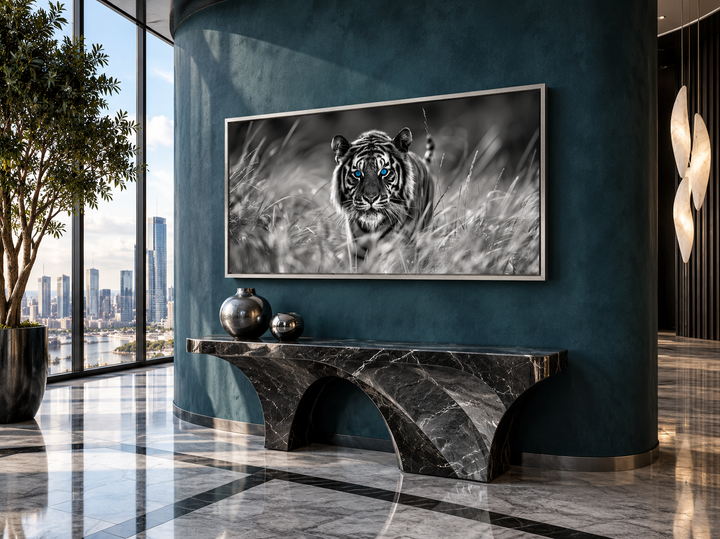 Black and white tiger wall art with blue eyes in a silver frame on a dark blue wall.