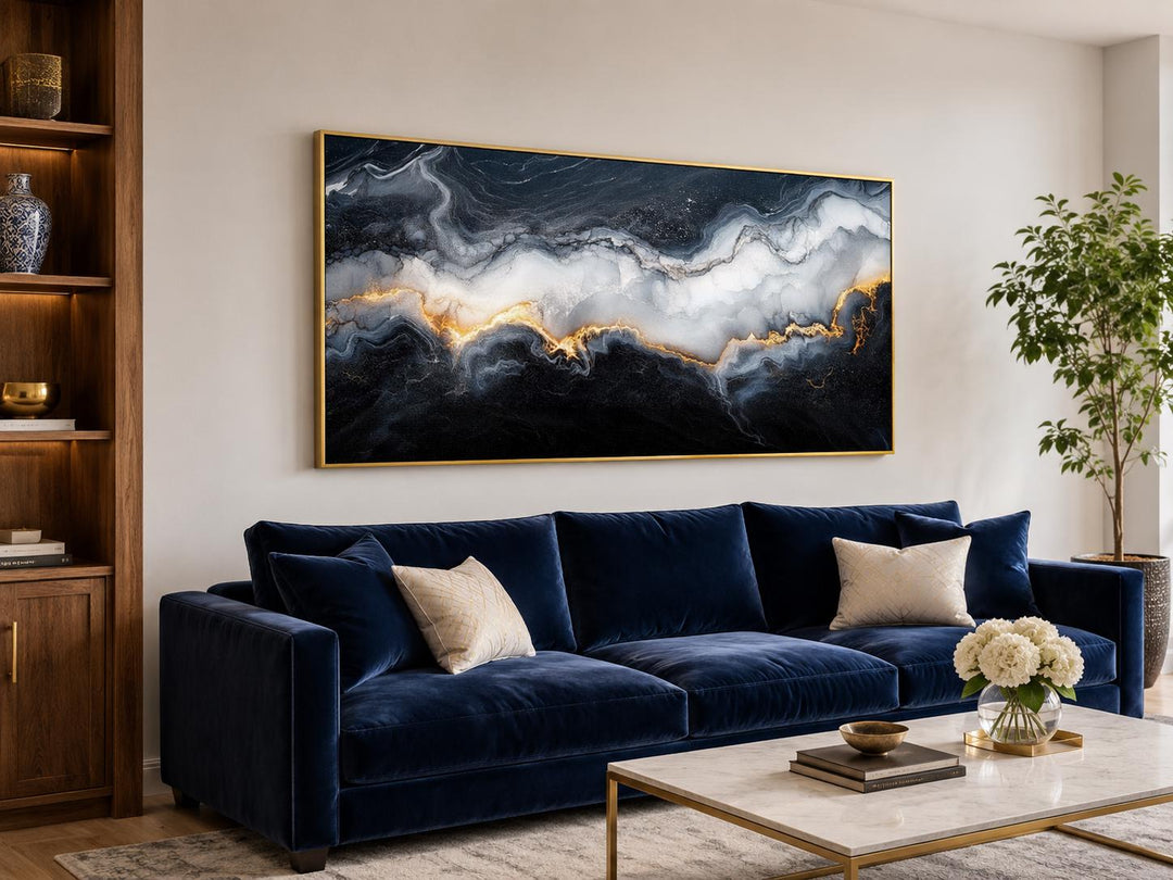 Black, white, and gold abstract marble canvas print hanging above a navy blue velvet sofa.