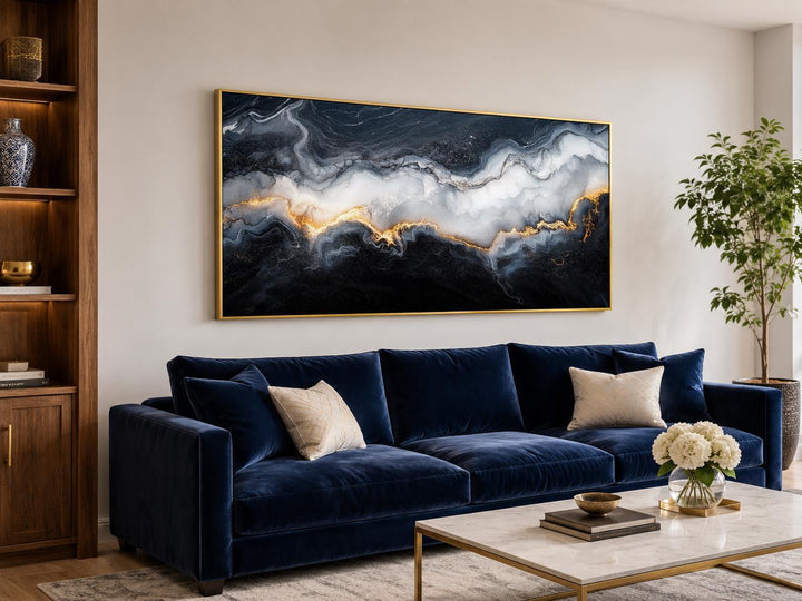 Black, white, and gold abstract marble canvas print hanging above a navy blue velvet sofa.