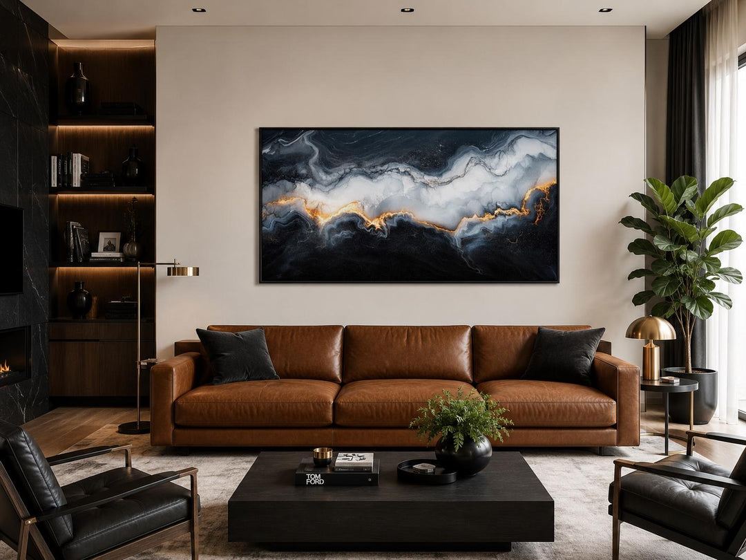 Black, white, and gold abstract marble canvas print centered above a brown leather sofa.