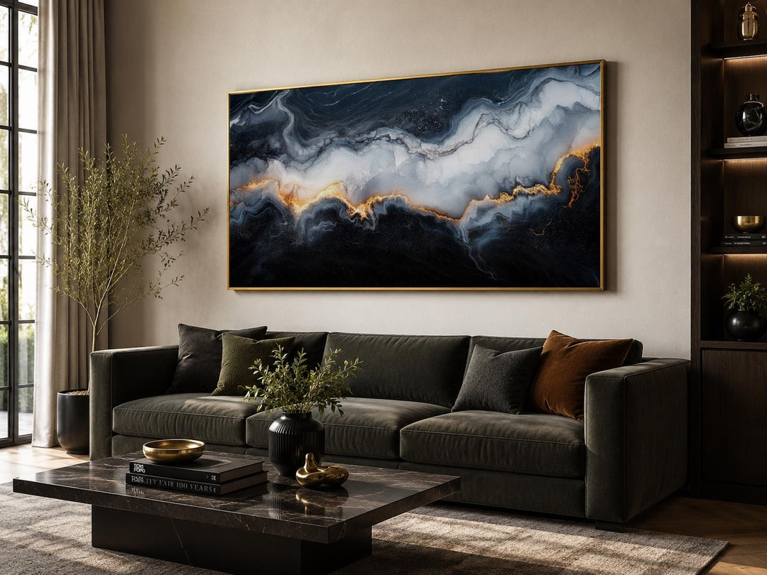 Large horizontal abstract marble canvas print with black, white, and gold veining above a sofa.