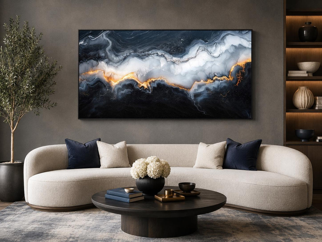Large horizontal abstract marble canvas print with black, white, and gold veining above a sofa.
