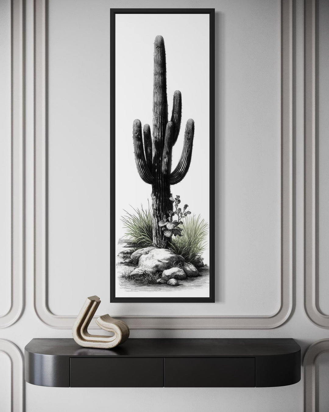 Tall narrow canvas art of a saguaro cactus in black and white with green accents on a paneled wall.