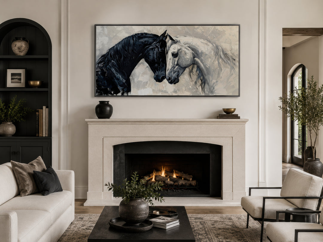 Framed canvas wall art of a black horse and a white horse touching heads above a fireplace.