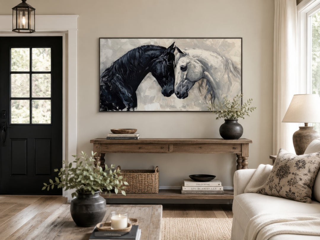 Framed canvas wall art of a black horse and a white horse touching heads above a wooden console.