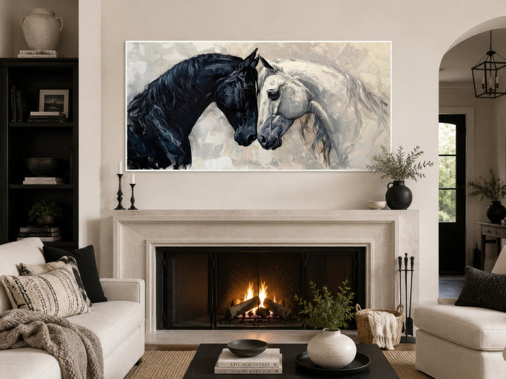 Framed canvas wall art of a black and white horse head-to-head above a fireplace in a modern room.