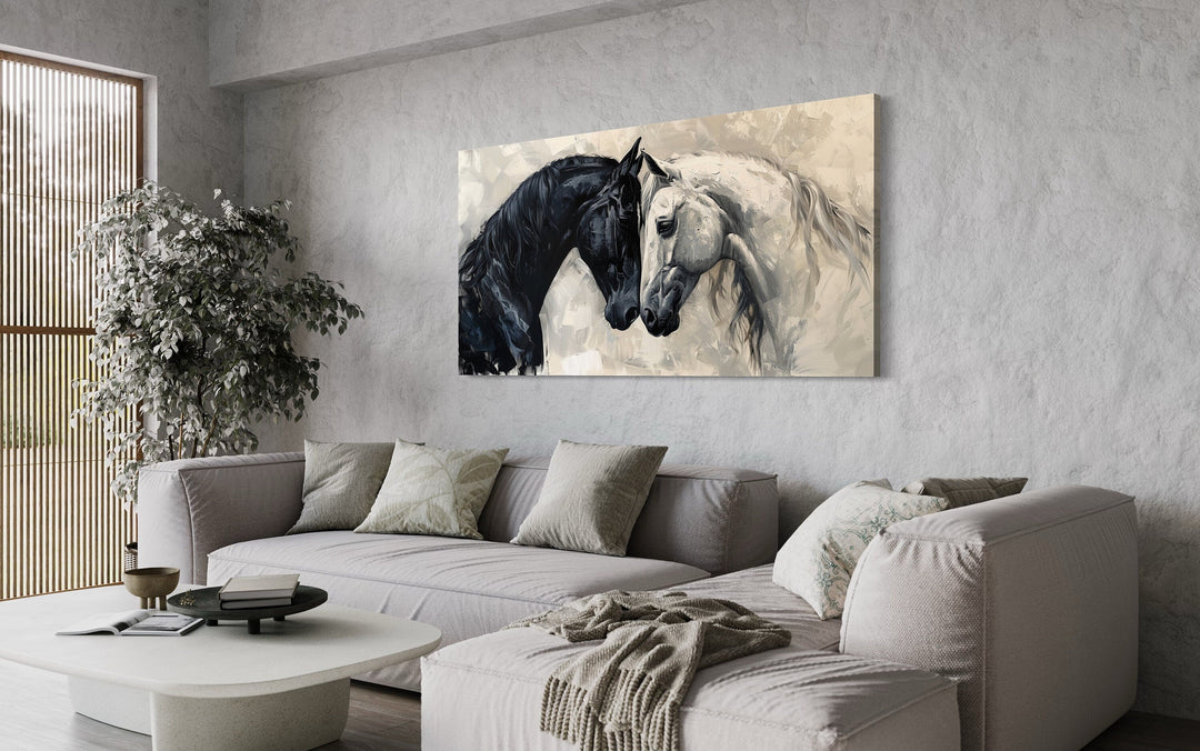 Framed canvas wall art of a black and white horse embracing, hung above a modern minimalist sofa.