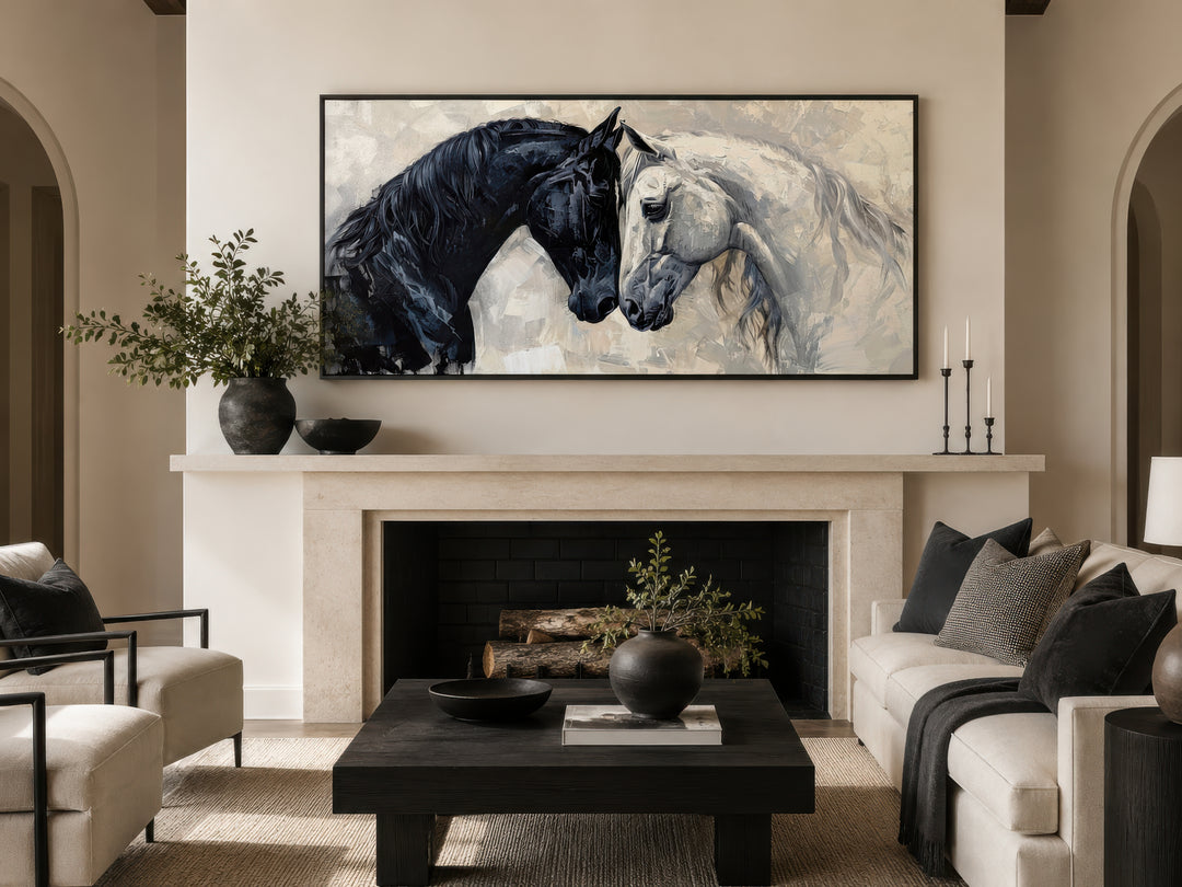 Framed canvas wall art of a black and white horse head-to-head above a modern fireplace.