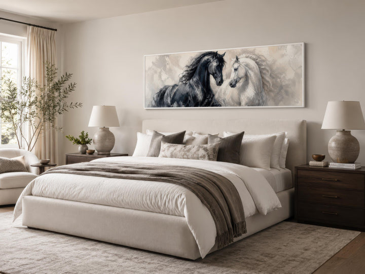 Long horizontal canvas print of a black and white horse above a bed in a neutral bedroom.