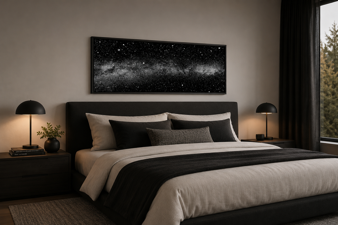 Framed black and white night sky canvas art above a bed in a modern bedroom.