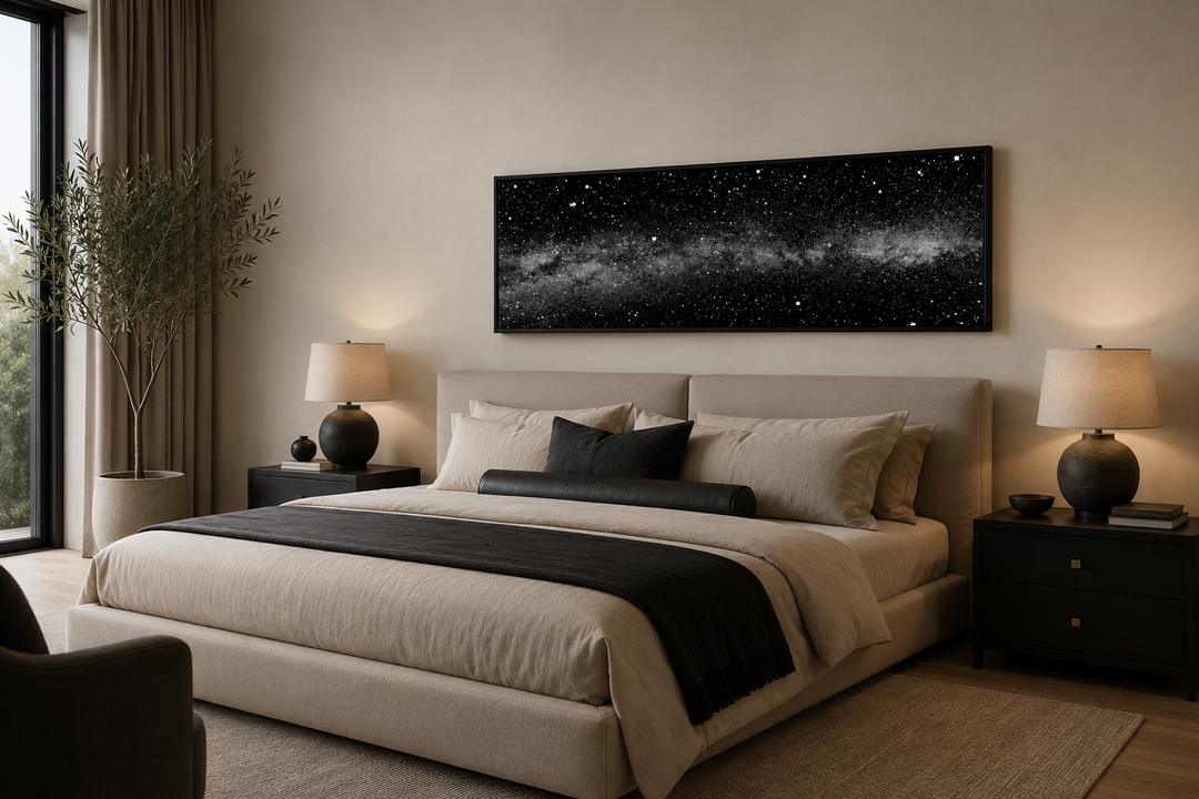 Framed black and white night sky art above a bed in a modern bedroom with celestial wall decor.
