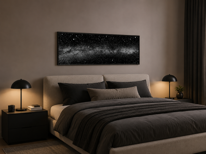Framed black and white night sky canvas art above a bed in a modern minimalist bedroom.
