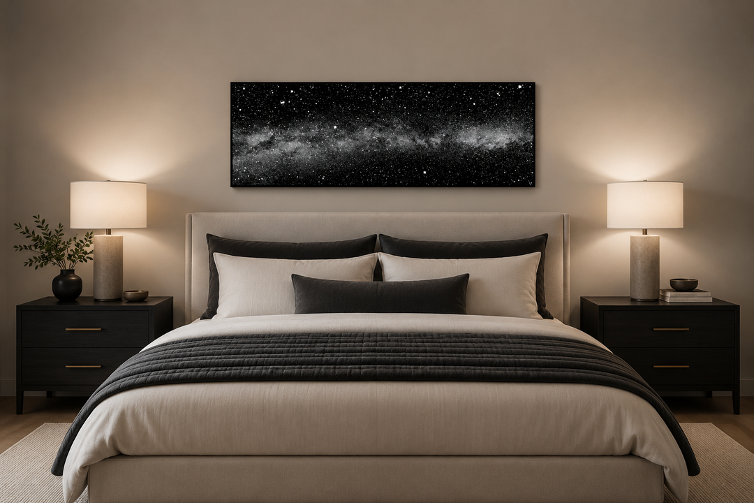 Framed black and white night sky canvas art above a bed in a modern bedroom.