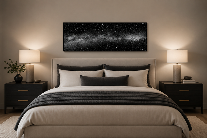Framed black and white night sky canvas art above a bed in a modern bedroom.