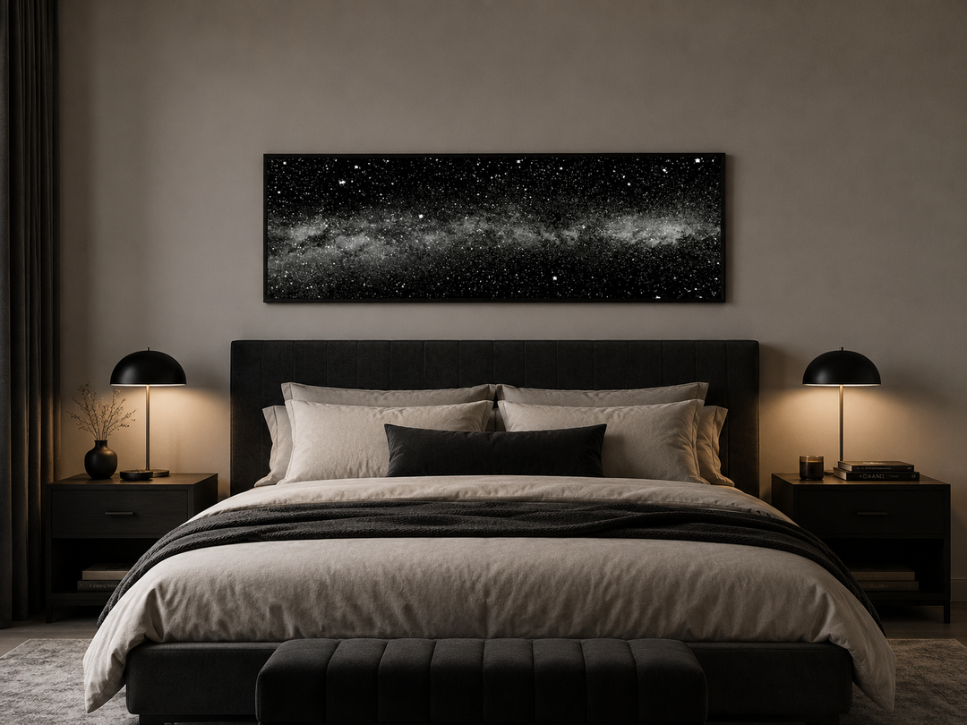 Framed black and white celestial wall art of a starry night sky above a modern bed.