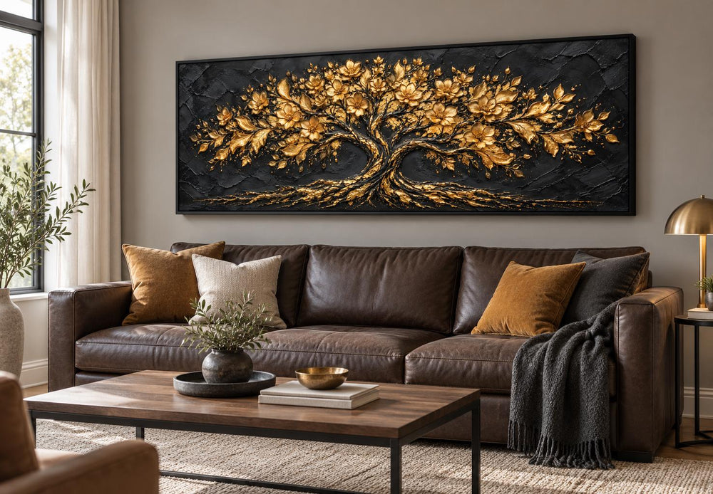 Black and gold flowering tree long horizontal canvas wall art above a brown leather sofa.