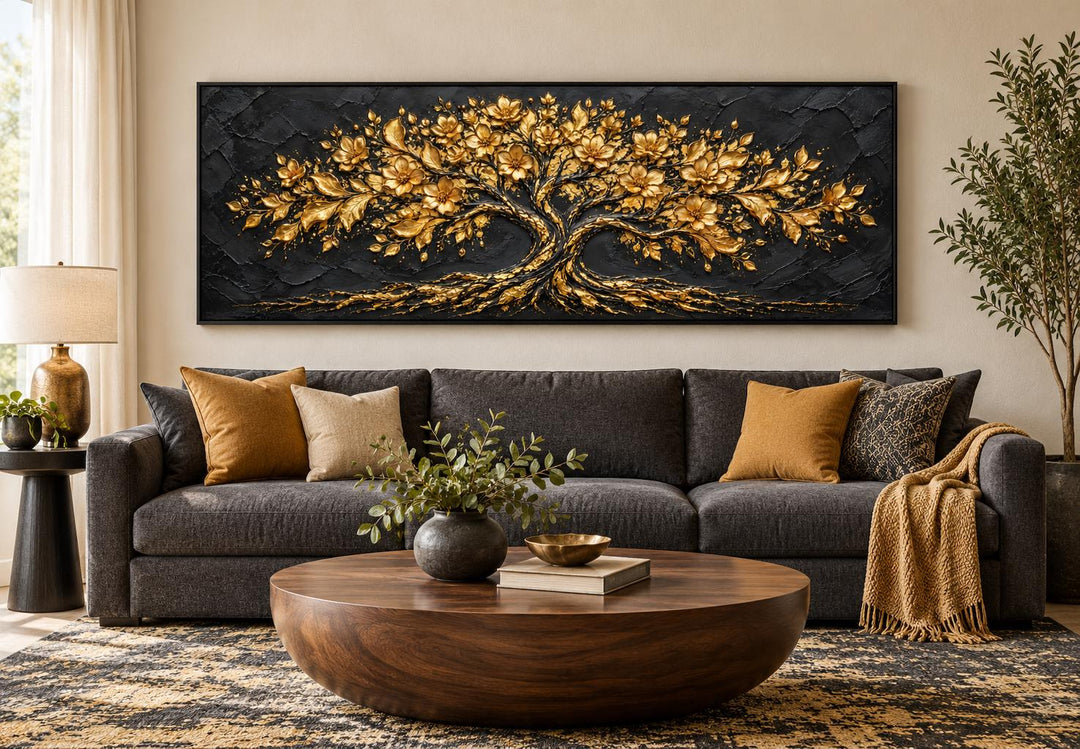 Black and gold flowering tree horizontal canvas wall art above a dark grey sofa in a living room.