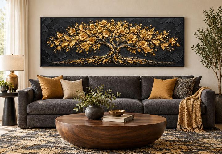 Black and gold flowering tree horizontal canvas wall art above a dark grey sofa in a living room.