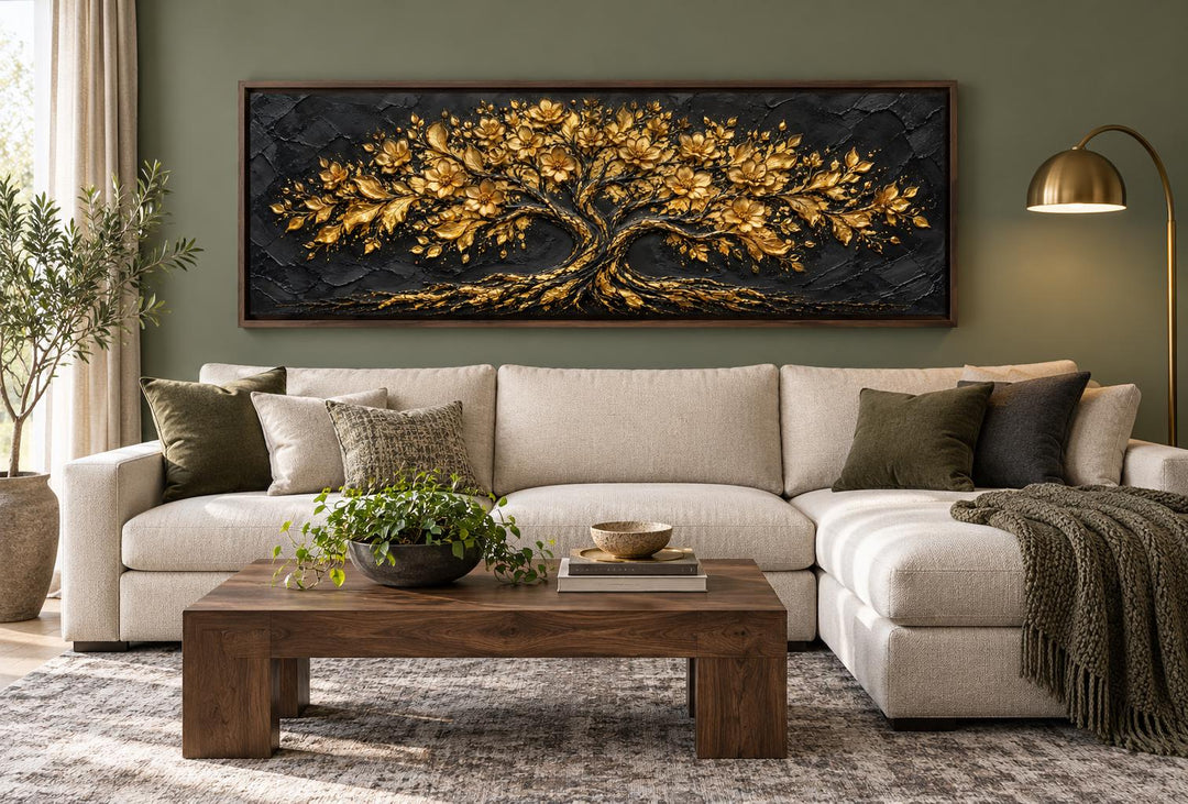 Horizontal canvas wall art of a golden flowering tree on a textured black background over a sofa.