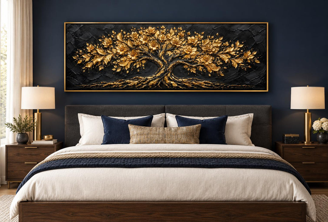 Black and gold flowering tree horizontal canvas wall art above a bed in a dark blue room.