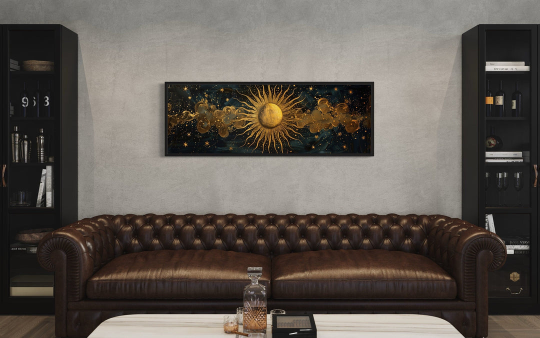 Black and gold sun horizontal framed canvas wall art hanging above a brown leather sofa.