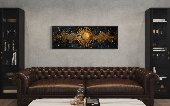 Black and gold sun horizontal framed canvas wall art hanging above a brown leather sofa.